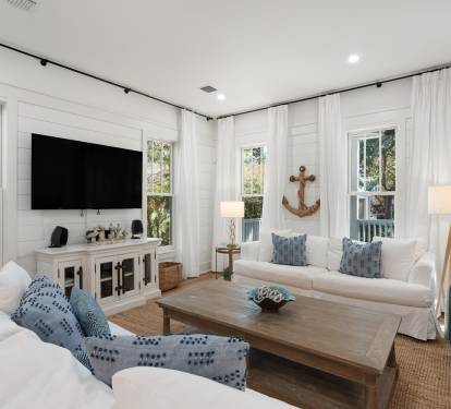 Sink into coastal comfort in this bright living room with nautical touches and natural light streaming through windows.