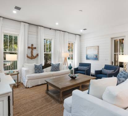 Relax in this coastal-inspired living room with nautical touches, crisp white shiplap walls, and plenty of natural light for your perfect getaway.