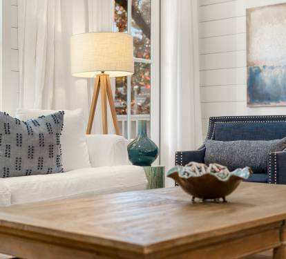 Relax in your bright living space with comfortable seating, coastal artwork, and natural light streaming through large windows.