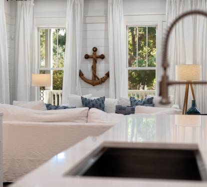 Your bright kitchen flows seamlessly into the cozy living space, where nautical charm meets modern comfort beneath soft natural light.