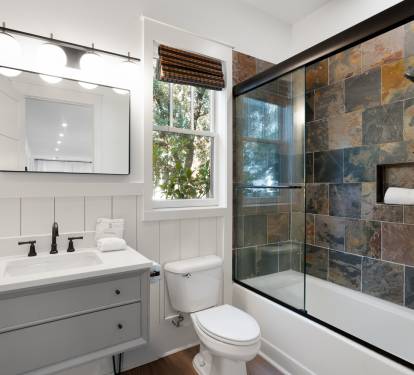 Unwind in your elegantly designed bathroom with stunning slate tile shower, modern fixtures, and peaceful garden views through charming windows.