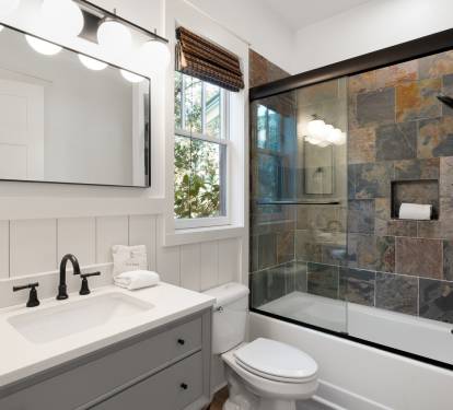 Unwind in your elegant bathroom featuring a luxurious slate-tiled shower and pristine vanity, perfectly designed for your comfort.