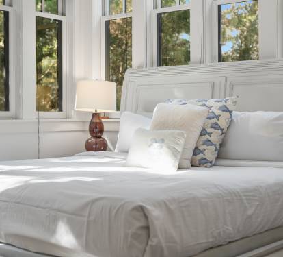 Wake up to sunlight streaming through expansive windows, creating your perfect morning sanctuary with crisp linens and peaceful tree views.