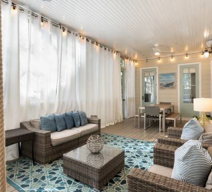 Your private porch retreat features cozy wicker seating, soft nautical pillows, and twinkling string lights creating the perfect spot to unwind.