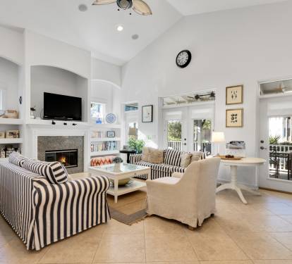 Your bright living space features cozy striped seating around a crackling fireplace, perfect for relaxing evenings with books from the built-in shelves.