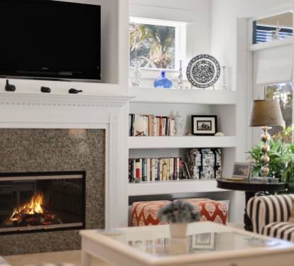 Relax in your bright living room where a crackling fireplace warms the space beneath your mounted TV and curated bookshelf.