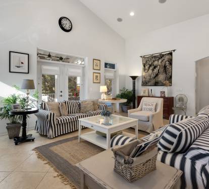 Relax in this bright, coastal-inspired living space with comfortable striped seating and charming nautical touches throughout.
