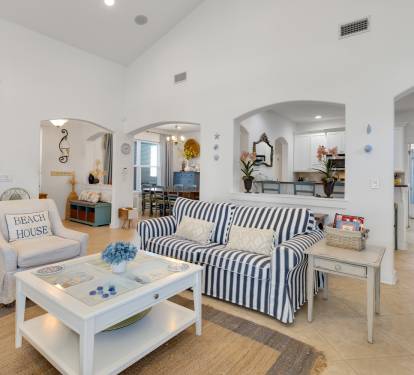 Relax in this charming coastal living space with its nautical-striped sofa, beach house charm, and open archways leading to your dining area.