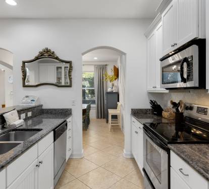 Your fully-equipped kitchen awaits with granite counters, stainless appliances, and elegant archways leading to bright living spaces.