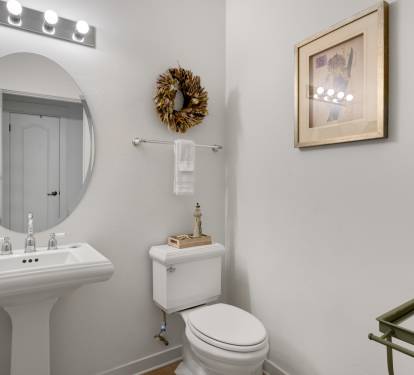 Fresh your morning routine in this thoughtfully appointed powder room, featuring elegant vanity lighting and welcoming touches.
