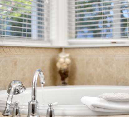 Slip into your private spa-like bathtub where warm natural light filters through blinds, creating the perfect sanctuary for relaxation.