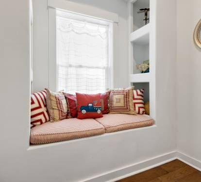 Curl up in your charming window nook with soft cushions and playful pillows, perfect for reading or simply watching the world go by.