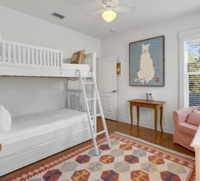 Your kids will love this charming bunk room with cozy white beds, playful artwork, and a reading nook by the window.