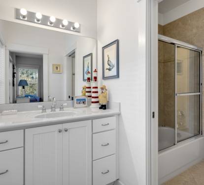 Your spacious bathroom features coastal charm with nautical décor, vanity lighting, and a relaxing shower-tub combo for unwinding after beach days.