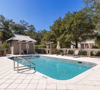 Oasis with crystal-clear pool waters surrounded by lush trees and comfortable lounging areas.