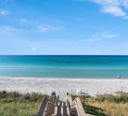 Pristine white sand beach with crystal-clear turquoise waters and convenient boardwalk access from the property area.
