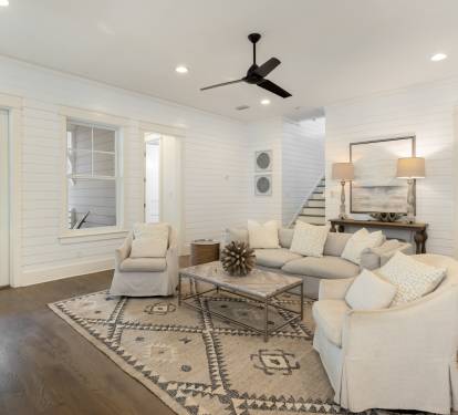 Relax in your spacious living room with plush sectional seating, stylish décor, and ceiling fan for perfect comfort.