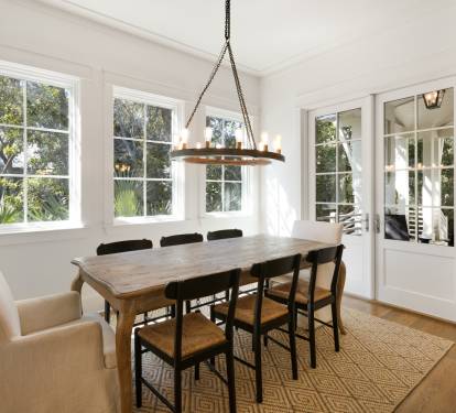 Gather around this elegant dining table where warm conversations flow beneath the rustic chandelier, with garden views framing every meal.
