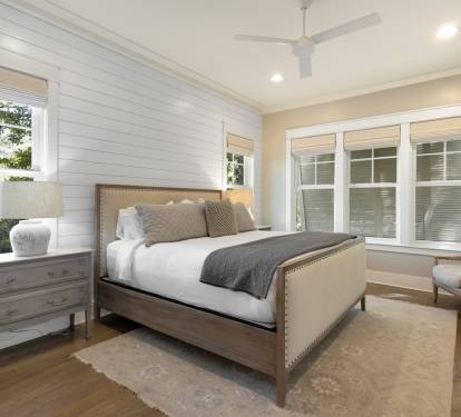 Unwind in this elegant bedroom with crisp white linens and natural light streaming through large windows.