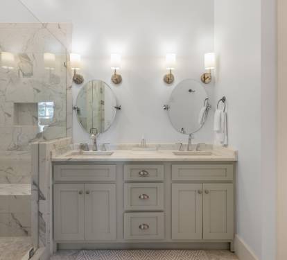 Step into your luxurious marble bathroom featuring dual sinks, elegant brass sconces, and a spacious glass-enclosed shower for ultimate relaxation.
