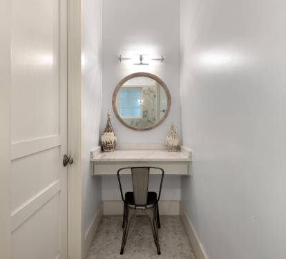 Your private vanity nook features elegant lighting and a cozy chair—perfect for morning routines or evening touch-ups.