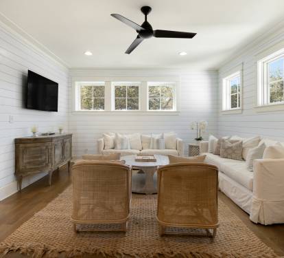 Sink into plush white sofas in this bright living room where shiplap walls and natural light create your perfect retreat space.