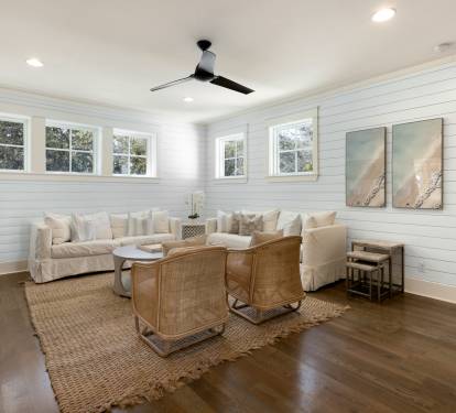Unwind in your bright coastal-style living room with plush seating, warm wood floors, and charming shiplap walls that create the perfect retreat.