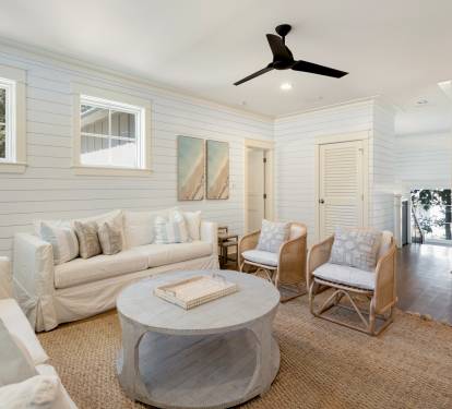 Unwind in your elegant living room featuring plush white seating, warm wood accents, and coastal charm perfect for peaceful evening conversations.
