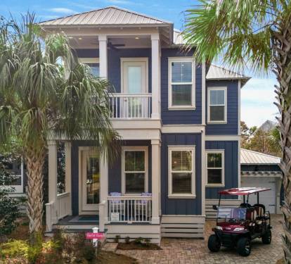 Charming coastal retreat with tropical palm trees and convenient golf cart parking for easy beach town exploration.