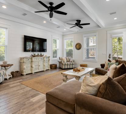 Sink into plush seating while ceiling fans keep you cool in this elegant living space with warm wood floors and abundant natural light.