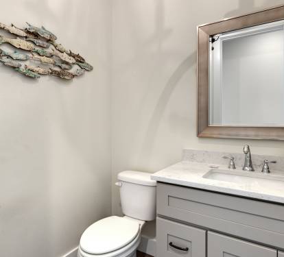 Your elegant powder room features coastal charm with artistic fish decor, marble countertops, and quality fixtures for your comfort.
