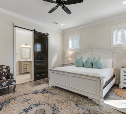 Your elegant bedroom sanctuary features plush bedding, antique-style furnishings, and a charming barn door leading to your private ensuite.