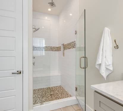 Step into your spa-like bathroom retreat with a stunning glass shower featuring mosaic accents and rainfall showerhead for ultimate relaxation.