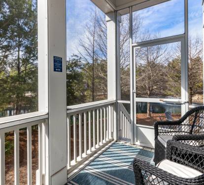 Step onto your screened porch where wicker chairs await your morning coffee, surrounded by peaceful tree views and natural light.