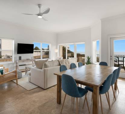 Relax in your bright, open living space where modern comfort meets coastal charm, with dining for eight and balcony access.
