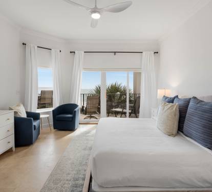Wake to coastal views from your bright bedroom, complete with balcony access and thoughtful touches like cozy seating.