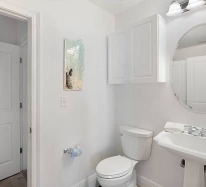 Step into your bright, spotless bathroom featuring a pedestal sink and round mirror—perfect for your morning routine.