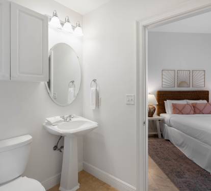 Your ensuite bathroom features a pristine pedestal sink and well-appointed fixtures, with your comfortable bedroom just steps away.