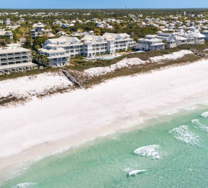 Stunning aerial view of beachfront properties along pristine white sand and turquoise waters in a peaceful coastal community.