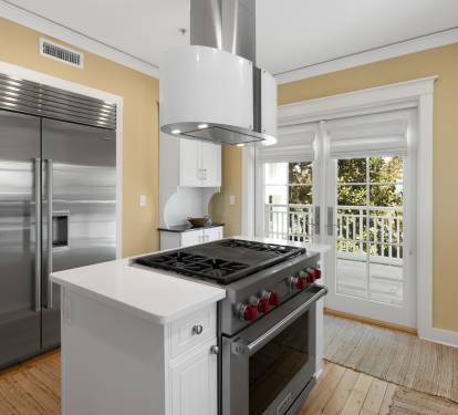 Your gourmet kitchen awaits with professional-grade appliances and warm natural light streaming through French doors to your private balcony.