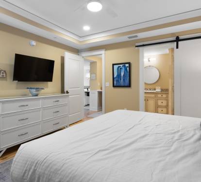 Unwind in your beautifully appointed bedroom featuring a plush bed, modern TV, and elegant sliding barn door bathroom access.