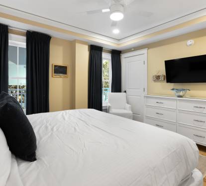 Sink into crisp white linens in your elegant bedroom, where warm golden walls and blackout curtains create a peaceful retreat.