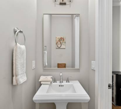 Refresh in your stylish powder room with coastal charm, featuring crisp white fixtures and thoughtful beach-themed touches.