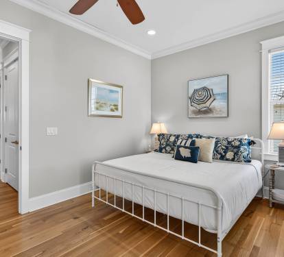 Relax in your peaceful bedroom with coastal charm, where warm wood floors and beach-inspired art create the perfect retreat.