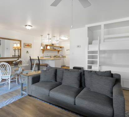 Relax on the plush gray sofa while kids enjoy built-in bunk beds. Open-concept design connects you to the kitchen and dining area.