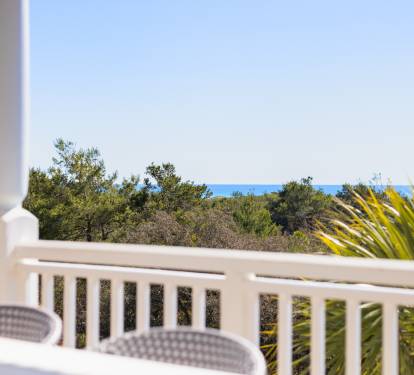 Peaceful balcony overlooks lush greenery and distant gulf views, creating the perfect spot for morning coffee or evening relaxation.