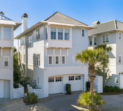 Beautiful coastal architecture showcases modern beach house design with palm-lined streets in an upscale neighborhood setting.