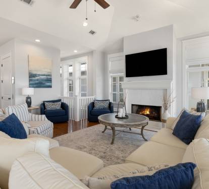Sink into plush sofas by your crackling fireplace, where navy accents and coastal art create the perfect spot for cozy evening conversations.