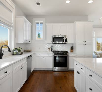 You'll love preparing meals in this bright, modern kitchen with gleaming white cabinets, spacious countertops, and premium appliances bathed in natural light.