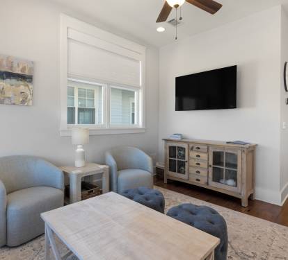Unwind in your cozy living room with plush seating, entertainment center, and calming coastal artwork creating the perfect retreat.
